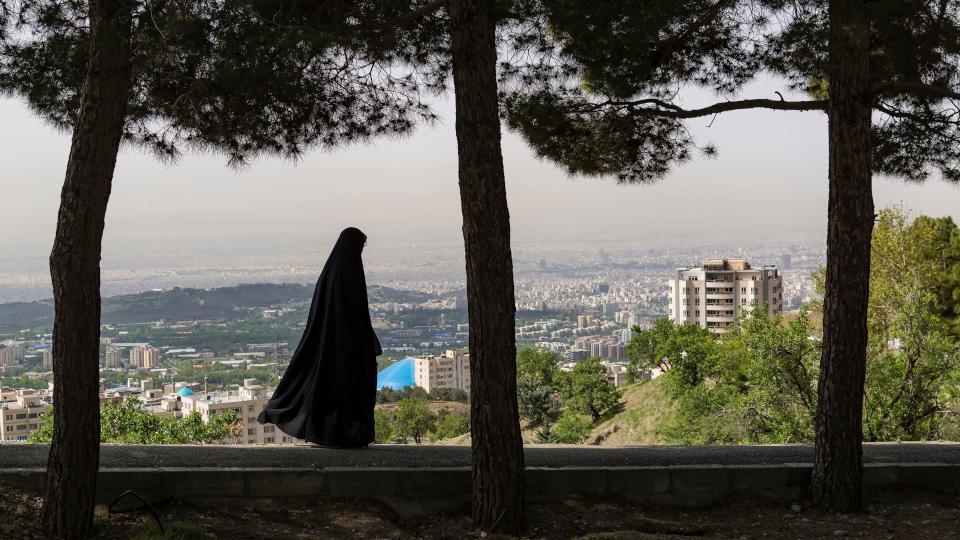 The Girl walks home in her black veil, with Tehran in the background.